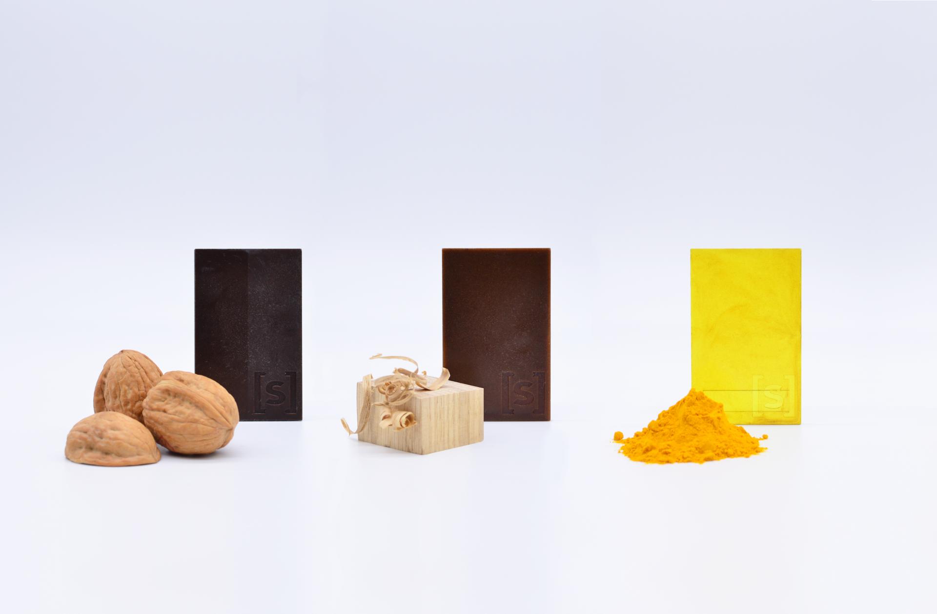 Sustainable bioplastics showcase various materials, including wood, nuts, and natural pigments for eco-friendly design solutions.