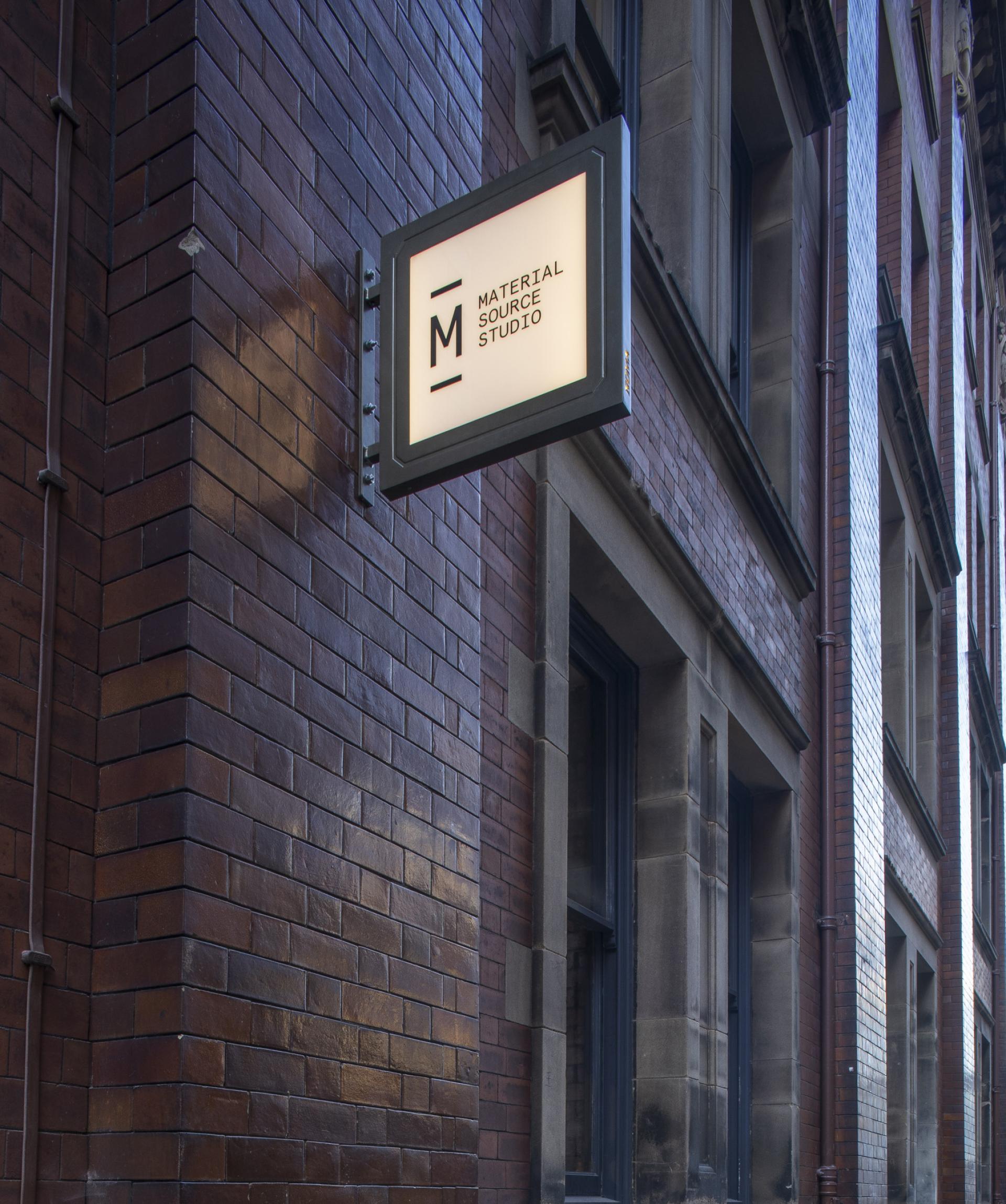 Signage for Material Source Studio on a brick building in Manchester's NOMA district, highlighting design and material innovation.