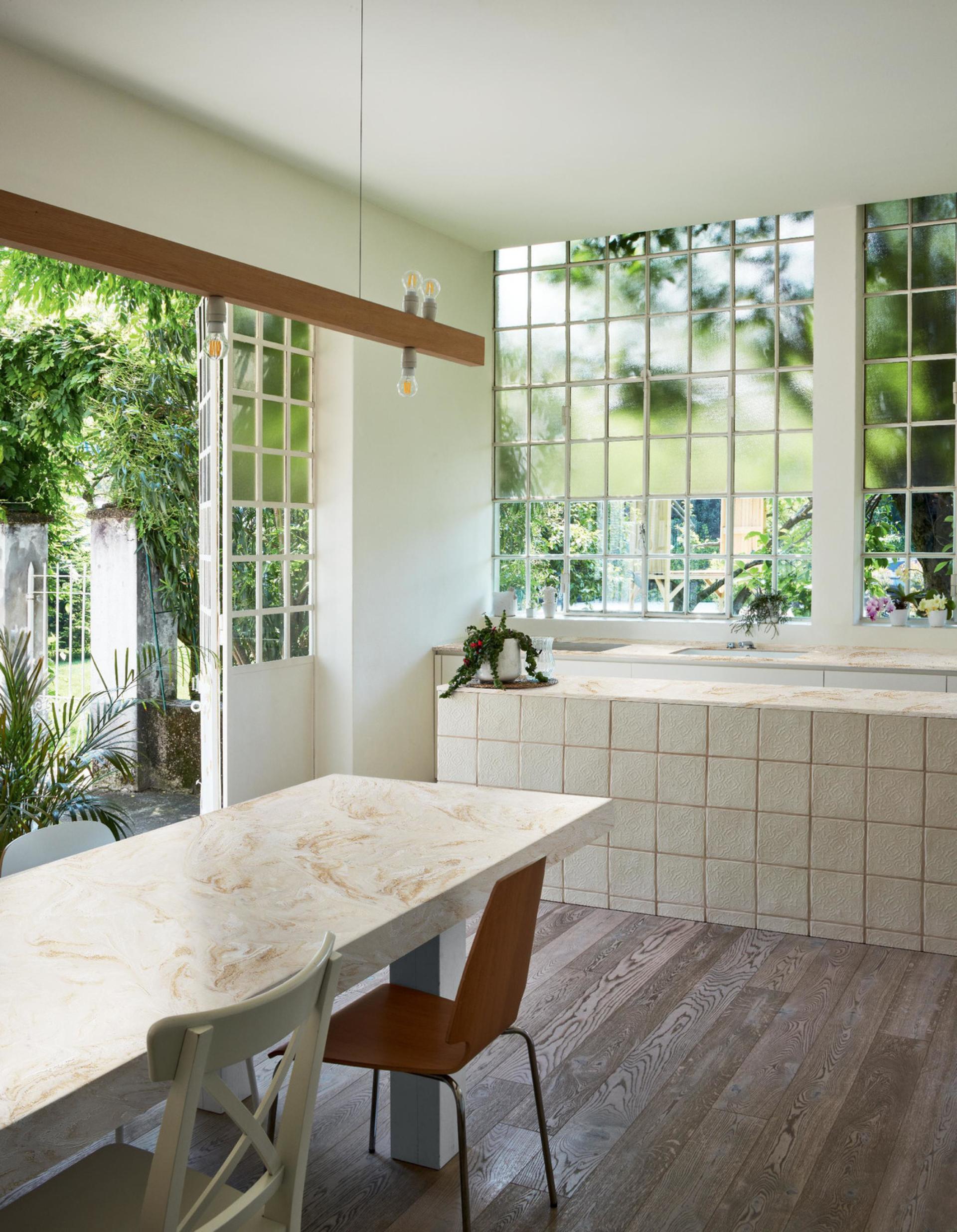 Stylish kitchen featuring a marble-patterned tabletop, textured surfaces, and abundant natural light through large windows.