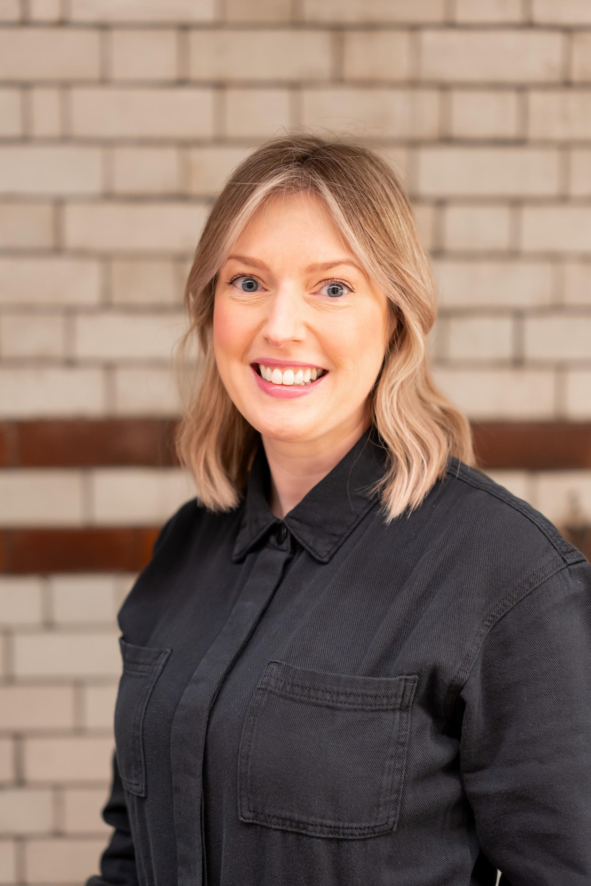 Professional woman smiling in a black shirt, highlighting discussions on sustainability and value engineering at a seminar.