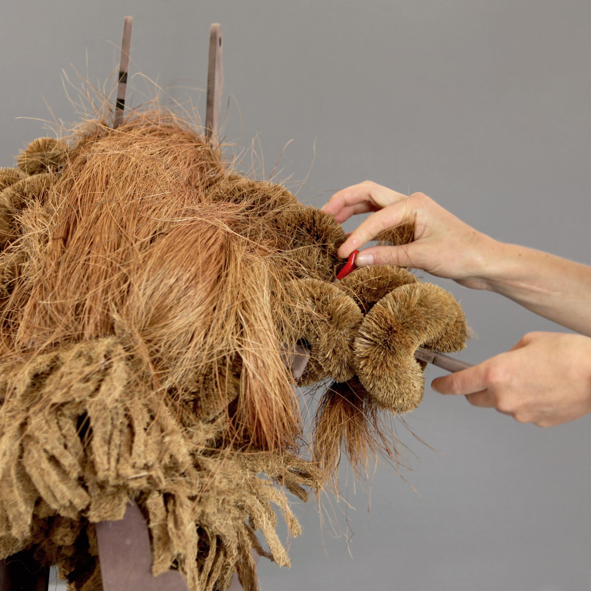 Hands working on a unique, textured sculpture made from natural materials, showcasing innovative design elements in architecture.