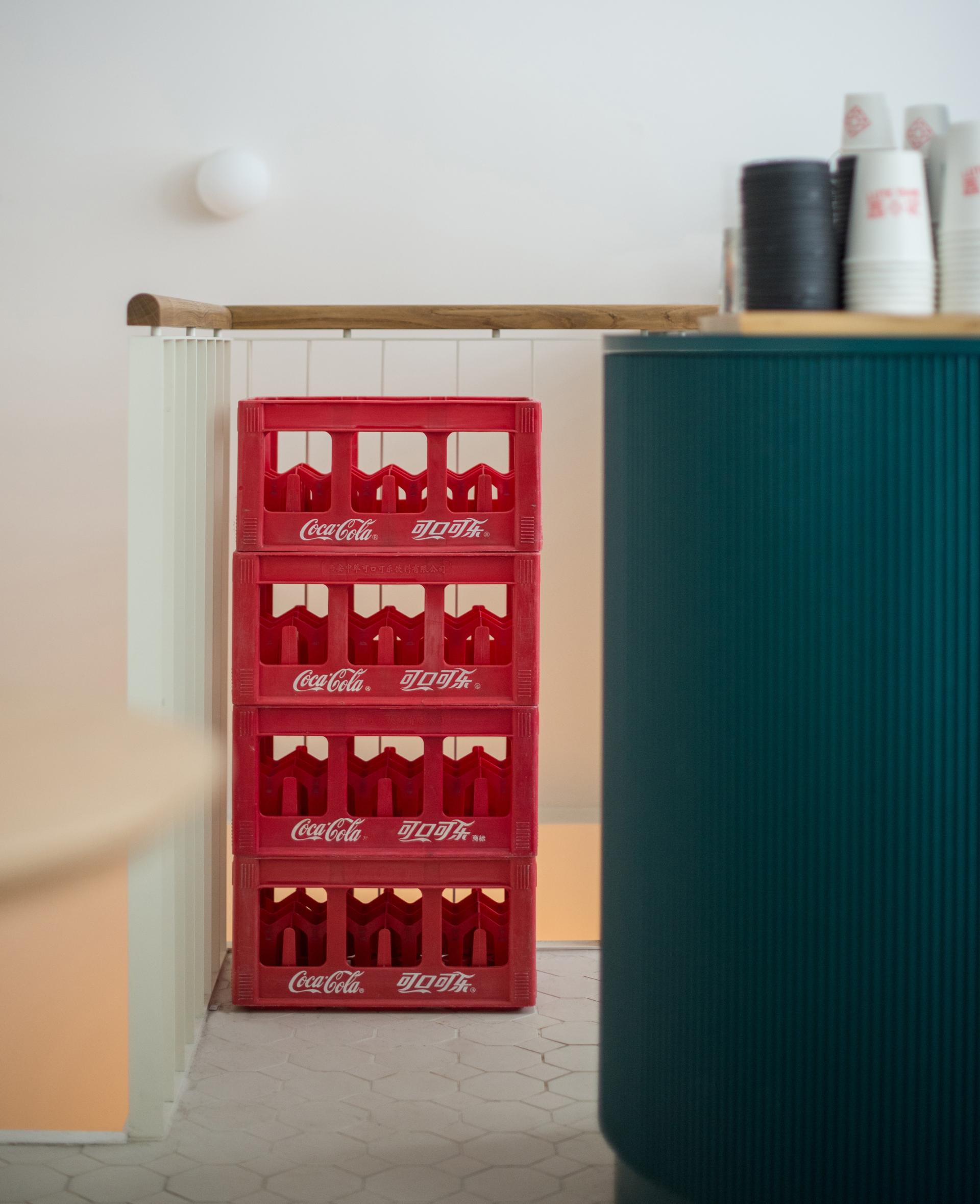 Stacked red Coca-Cola crates in a modern Parisian Bing Sutt interior design by HOP Architects, featuring stylish elements.