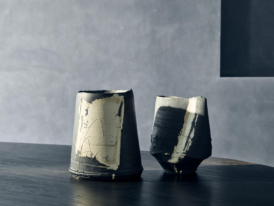 Artistic ceramic vases displayed on a wooden table, showcasing unique textures and a blend of dark and light colors.