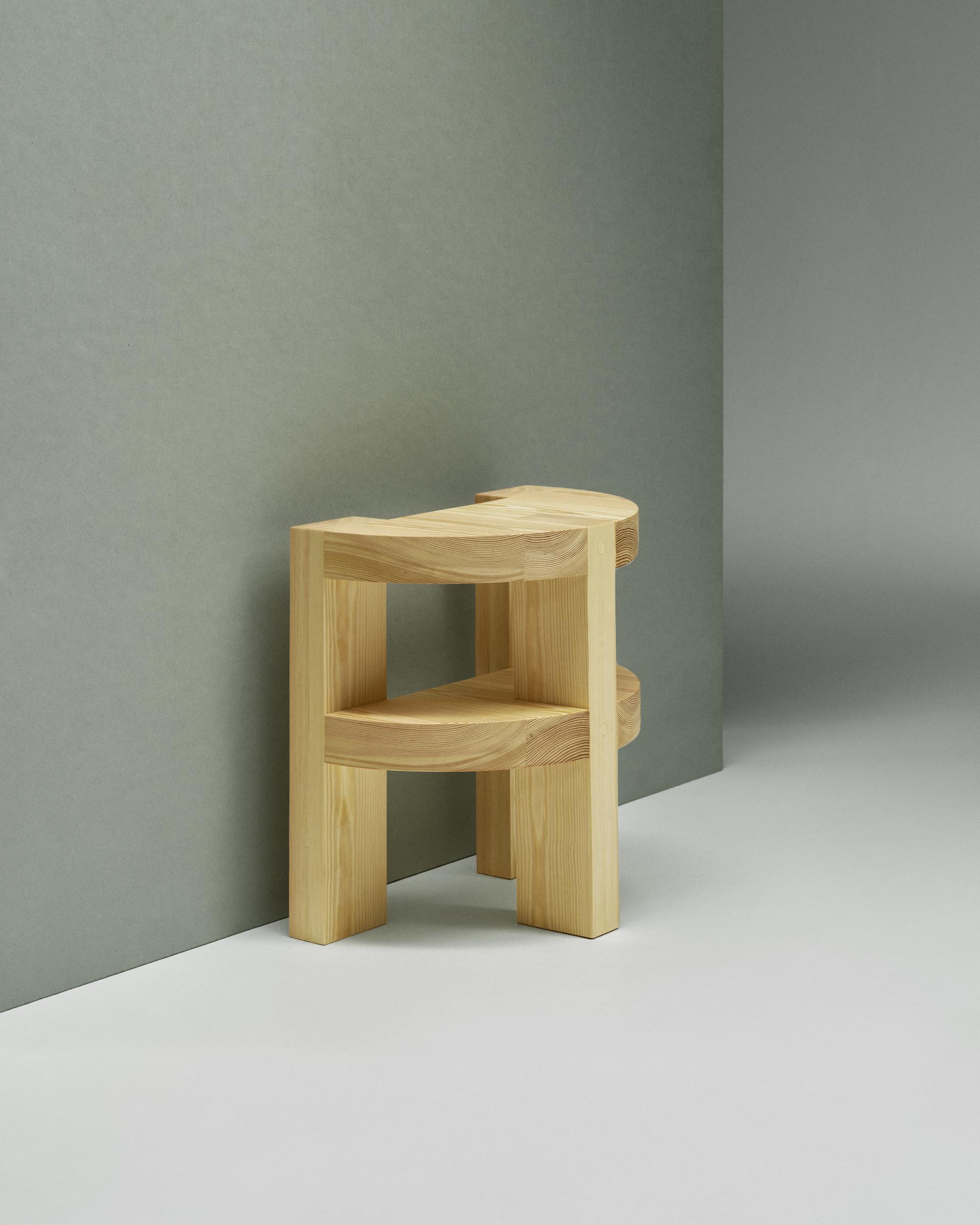 Sculptural wooden stool against a muted wall, showcasing Norwegian craftsmanship and circular design principles at Milan Design Week.