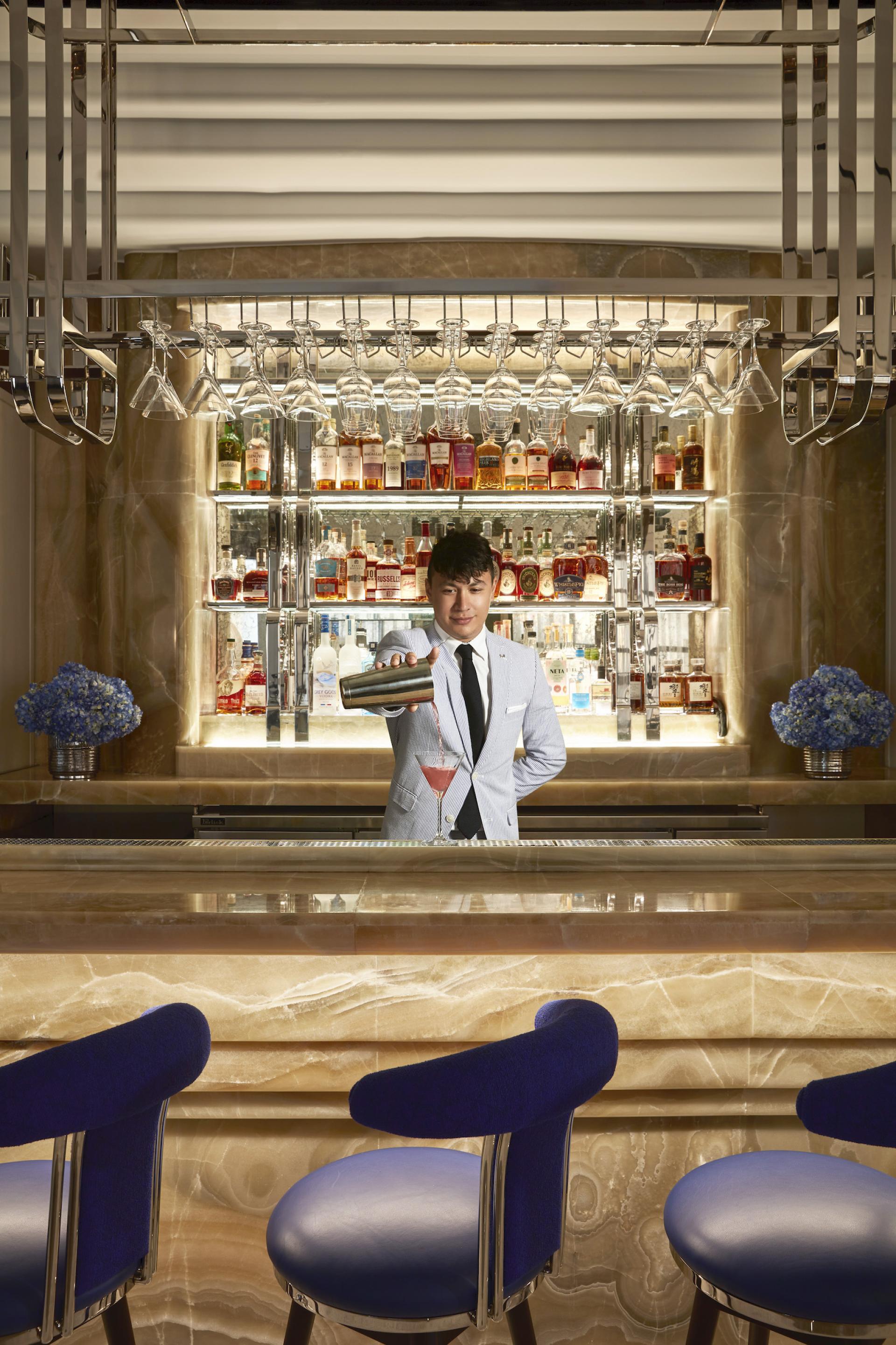 A bartender pours a cocktail at the Maybourne Bar, showcasing its elegant Art Deco design and Californian style.