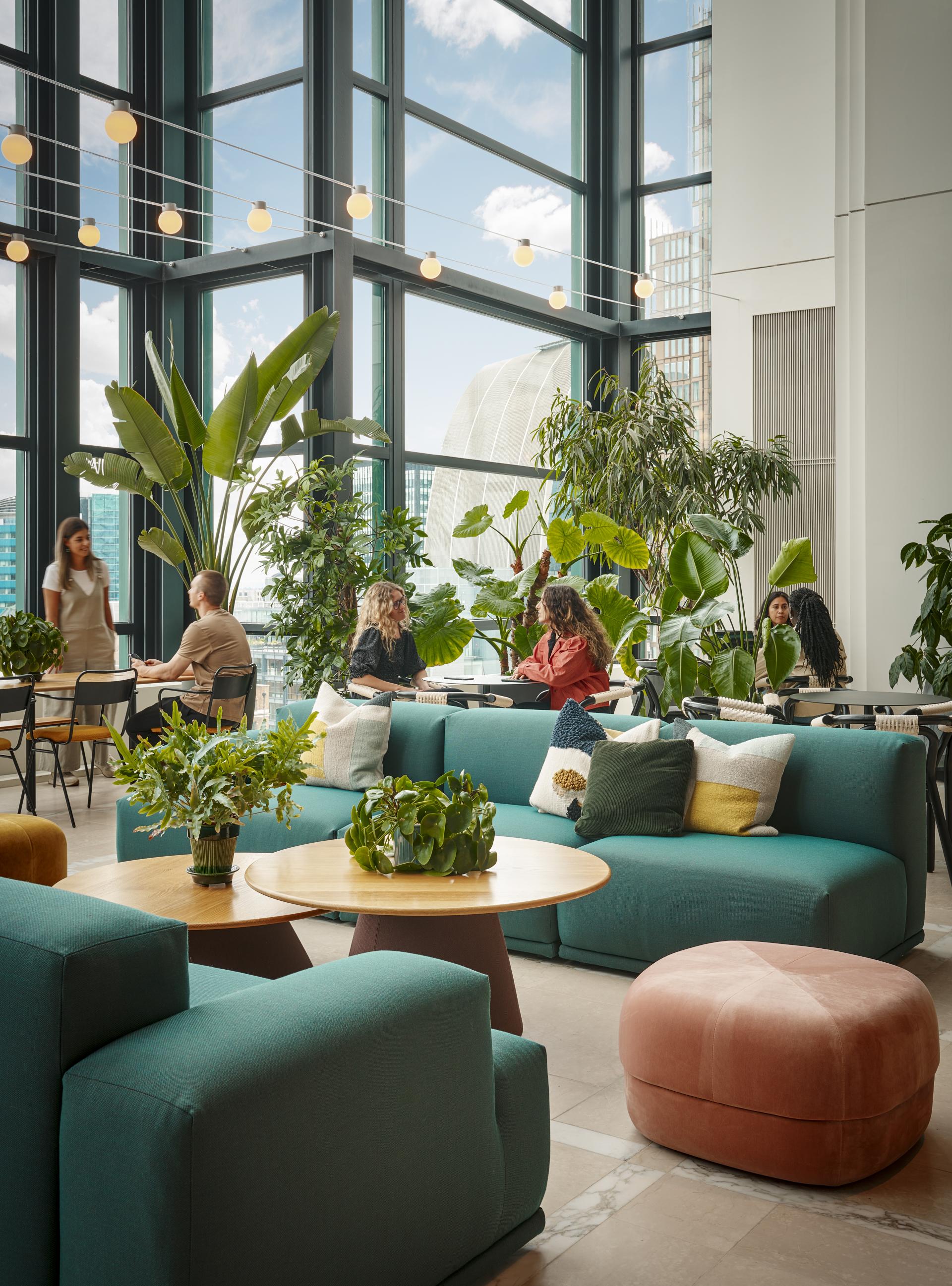 Bright and inviting office space featuring sustainable design elements, lush greenery, and collaborative seating arrangements.