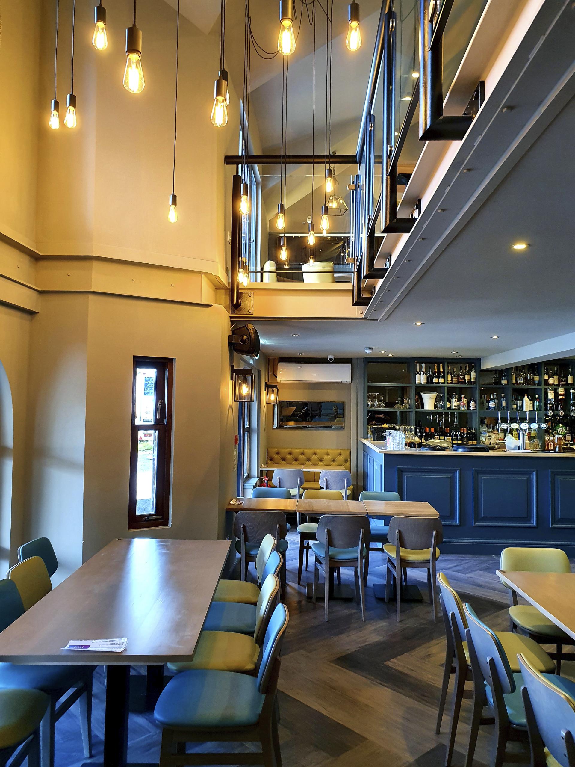 Modern hospitality venue with colorful seating, stylish lighting, and a well-stocked bar, reflecting adaptability and experience in design.