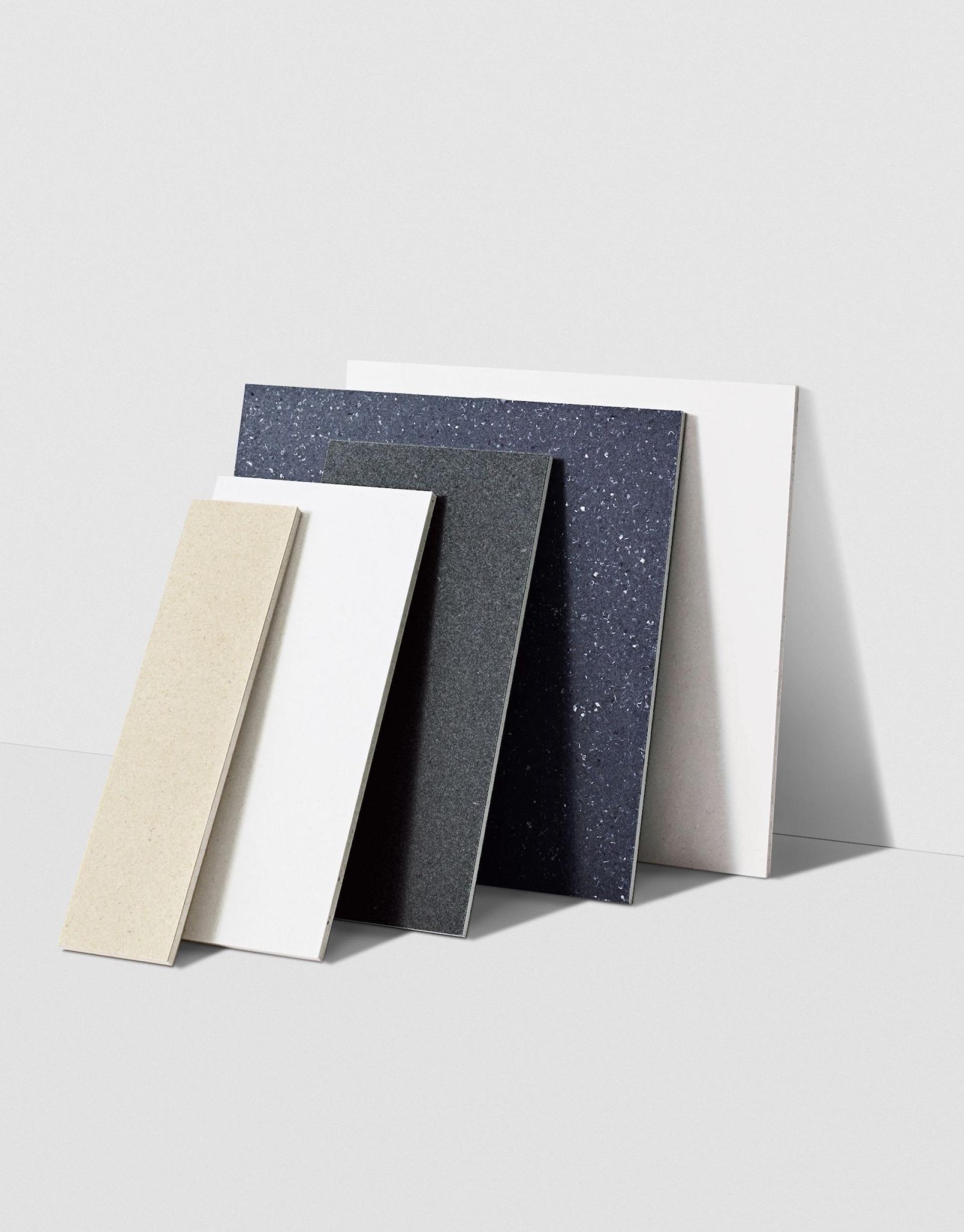 Samples of various design materials showcasing neutral and dark tones, emphasizing sustainable choices in interior design.