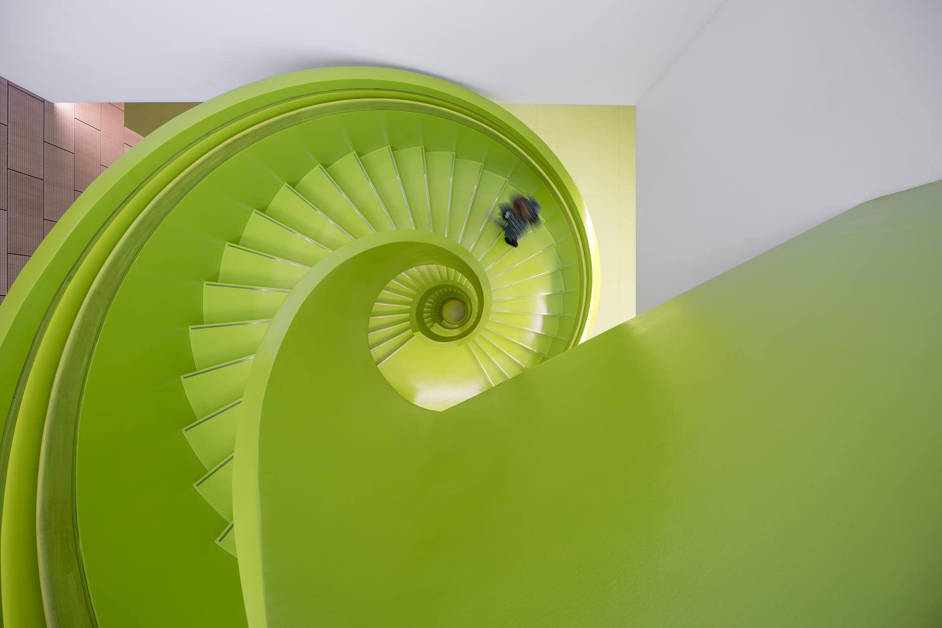 Bright green spiral staircase in a modern LEGO building, promoting creativity and innovation among employees.