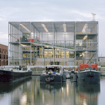 New multipurpose school building by Xaveer De Geyter Architects, overlooking docked boats in the Koopvaardijlaan harbour area.