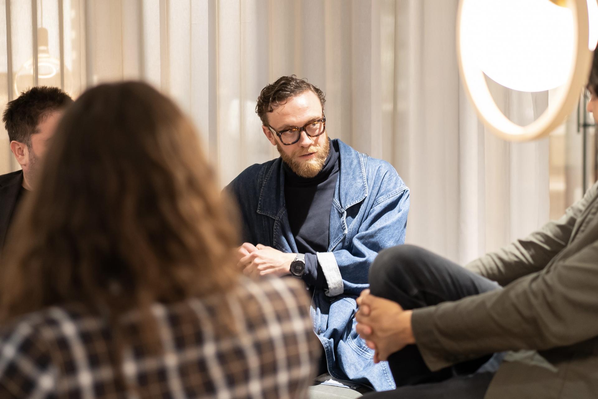Discussion among individuals in a modern workspace during a technology seminar, emphasizing collaboration and communication.