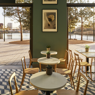Stylish café interior featuring Caesarstone quartz table surfaces, wooden chairs, and artistic nature-inspired wall decor.