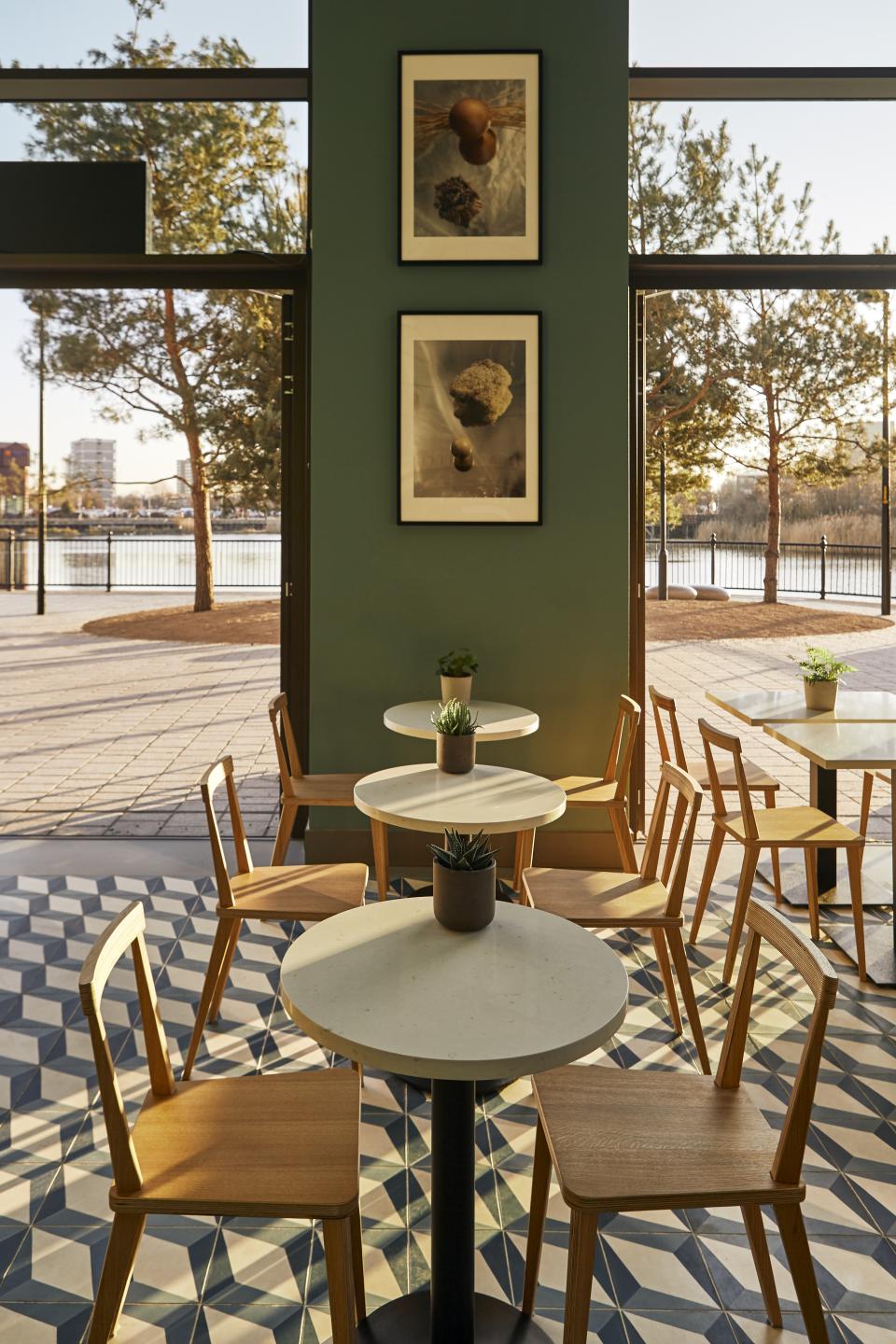 Stylish café interior featuring Caesarstone quartz table surfaces, wooden chairs, and artistic nature-inspired wall decor.
