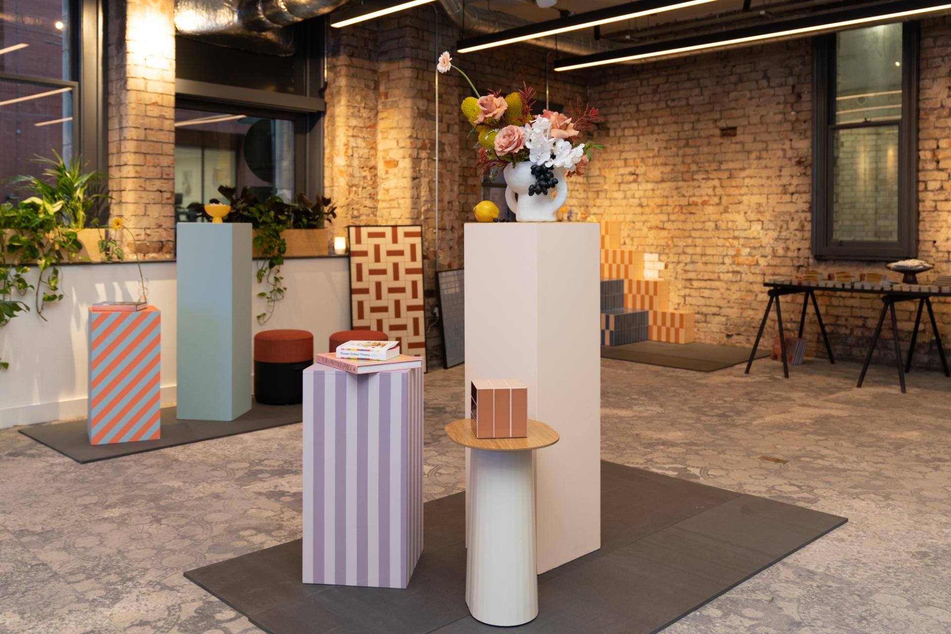 Colorful display featuring sculptural pedestals and floral arrangements, showcasing Tekla Severin and Ramona Macchi’s Färgblock collection.