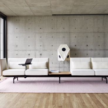 Minimalist office seating system by Vitra featuring sleek white sofas, adaptable workspace, and modern decor elements.