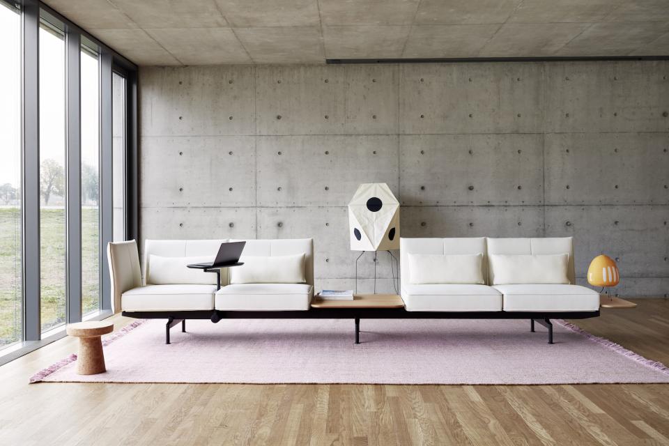 Minimalist office seating system by Vitra featuring sleek white sofas, adaptable workspace, and modern decor elements.