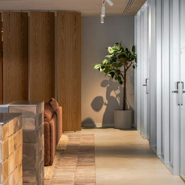 Modern office interior featuring flexible workspace design with natural lighting and greenery for enhanced employee wellbeing.