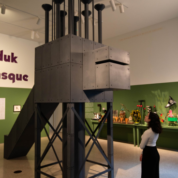 Exhibition space showcasing a large architectural model by John Hejduk, with a viewer admiring the intricate design.