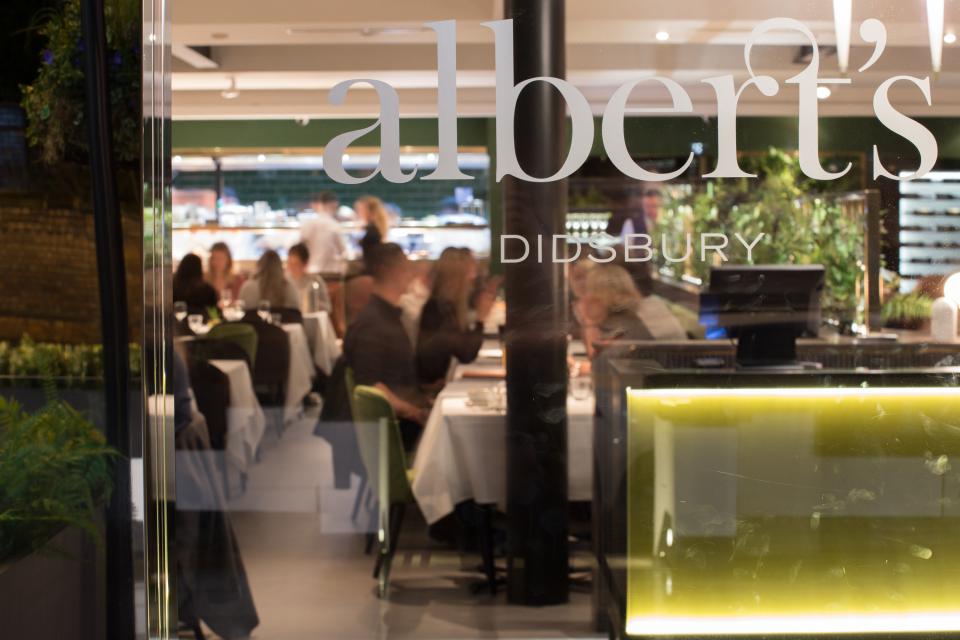 Stylish interior view of Albert's Didsbury, showcasing dining patrons amidst a vibrant, modern atmosphere.
