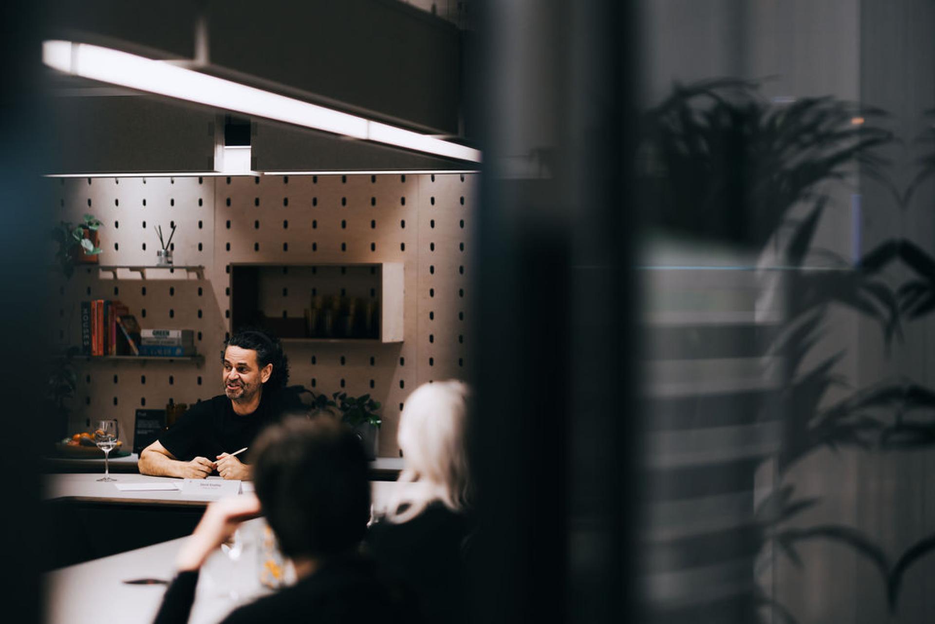 Engaged speaker discussing biomaterials with an attentive audience in a modern, sustainable event space.