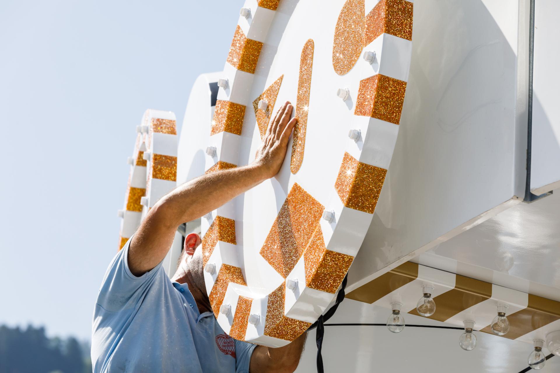 A person adjusts the sparkling, colorful elements of the whimsical Carousel art piece by Jaime Hayon.
