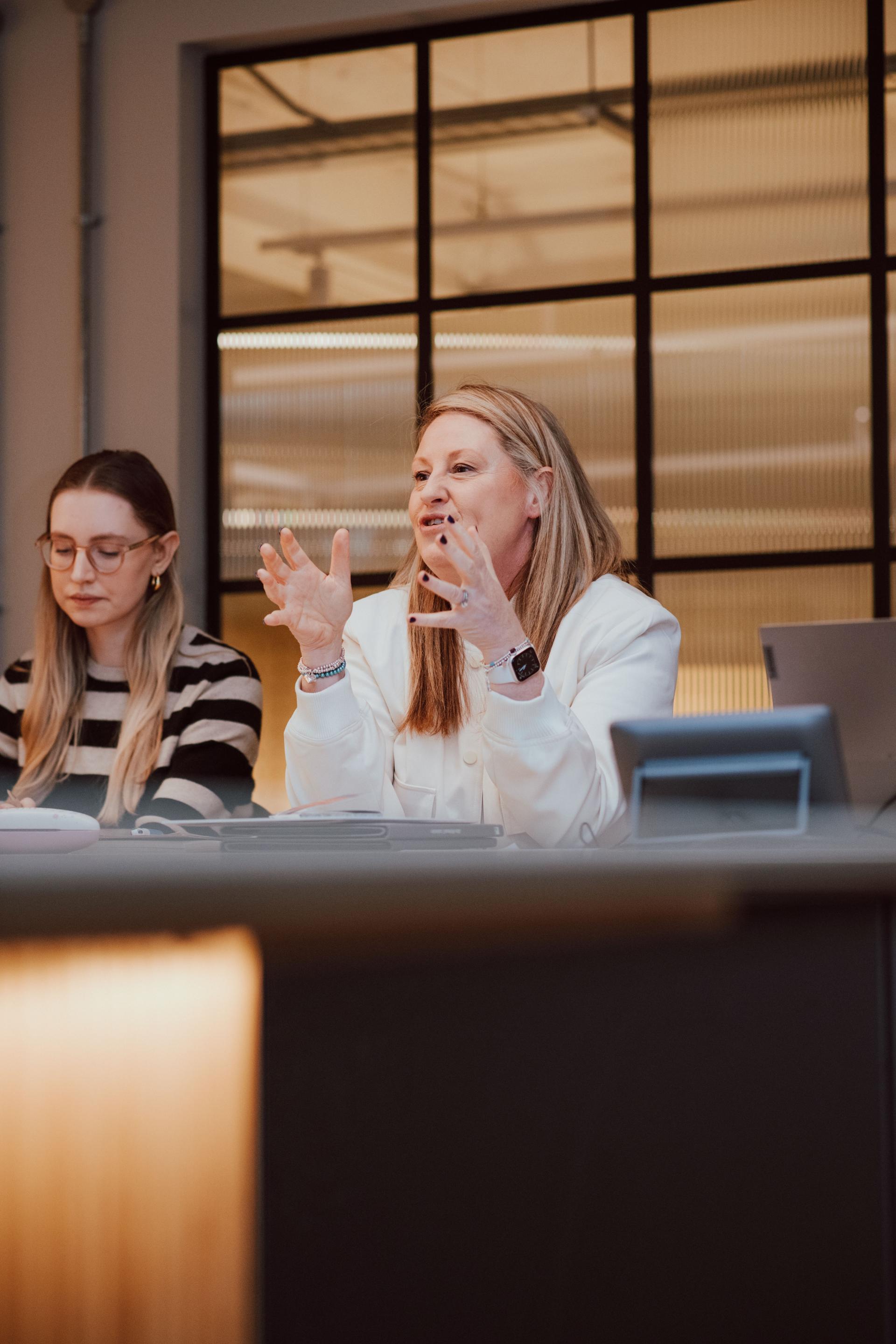 Women engaging in a creative discussion on interior design collaboration with Manchester Academy in a modern meeting space.