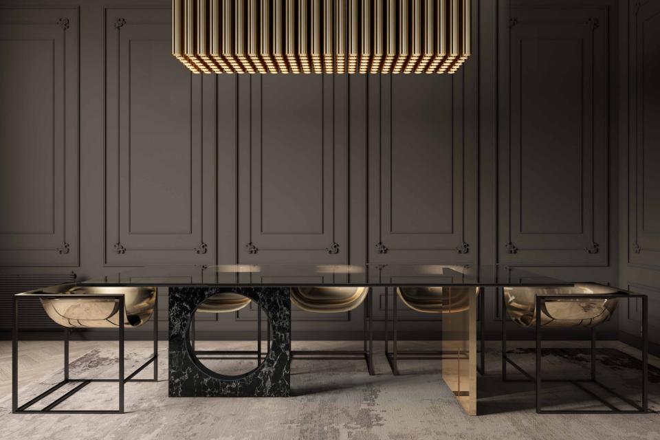 Elegant minimalist dining table featuring a black marble base and gold chairs, under a geometric light fixture.