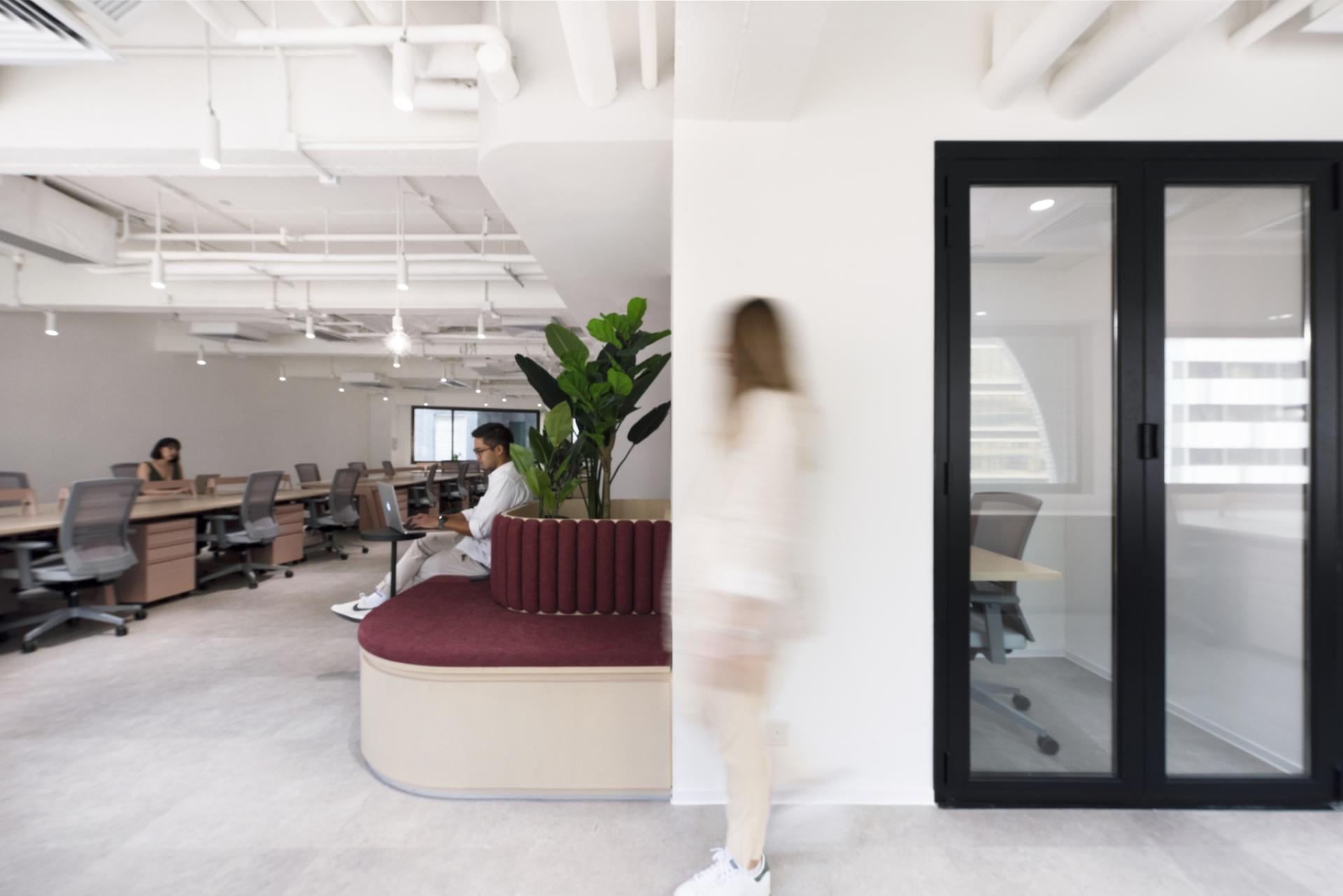 Modern office interior for Charterhouse, featuring collaborative spaces, plants, and individuals engaged in work activities.