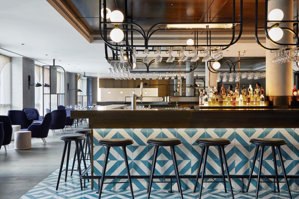 Stylish bar area with modern decor, featuring geometric tiled design and illuminated bottles at PURO Kraków Kazimierz.