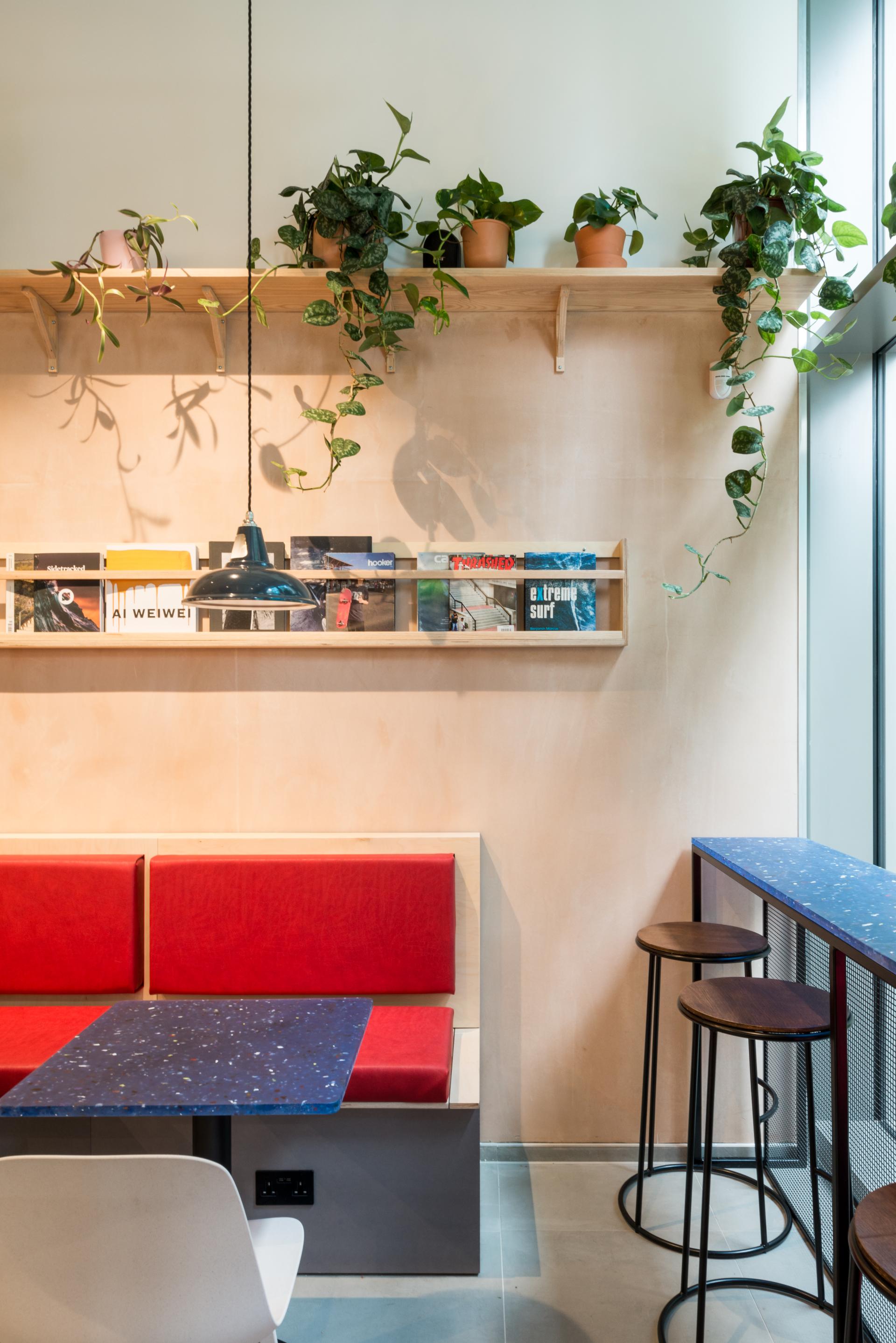 Stylish interior featuring red seating, blue speckled table, and greenery, highlighting sustainable design aesthetics by Smile Plastics.