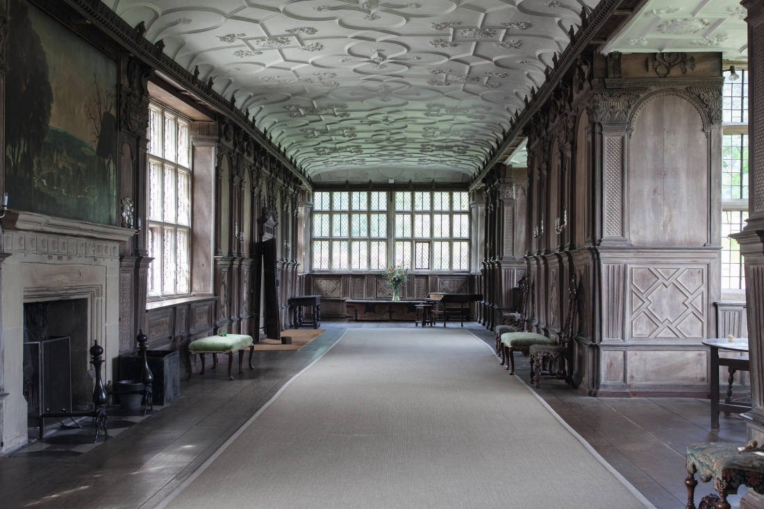 Haddon Hall. The Long Gallery. A union of natural surfaces; wood, stone and plaster with no colour, creating a dry beauty. Rex Whistler’s painting, a romantic vision of the house in its landscape is on the left above the fireplace.