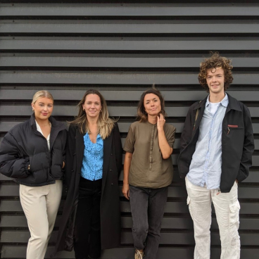 Four diverse team members from Auric Design stand confidently against a sleek black backdrop, embodying collaboration and creativity.