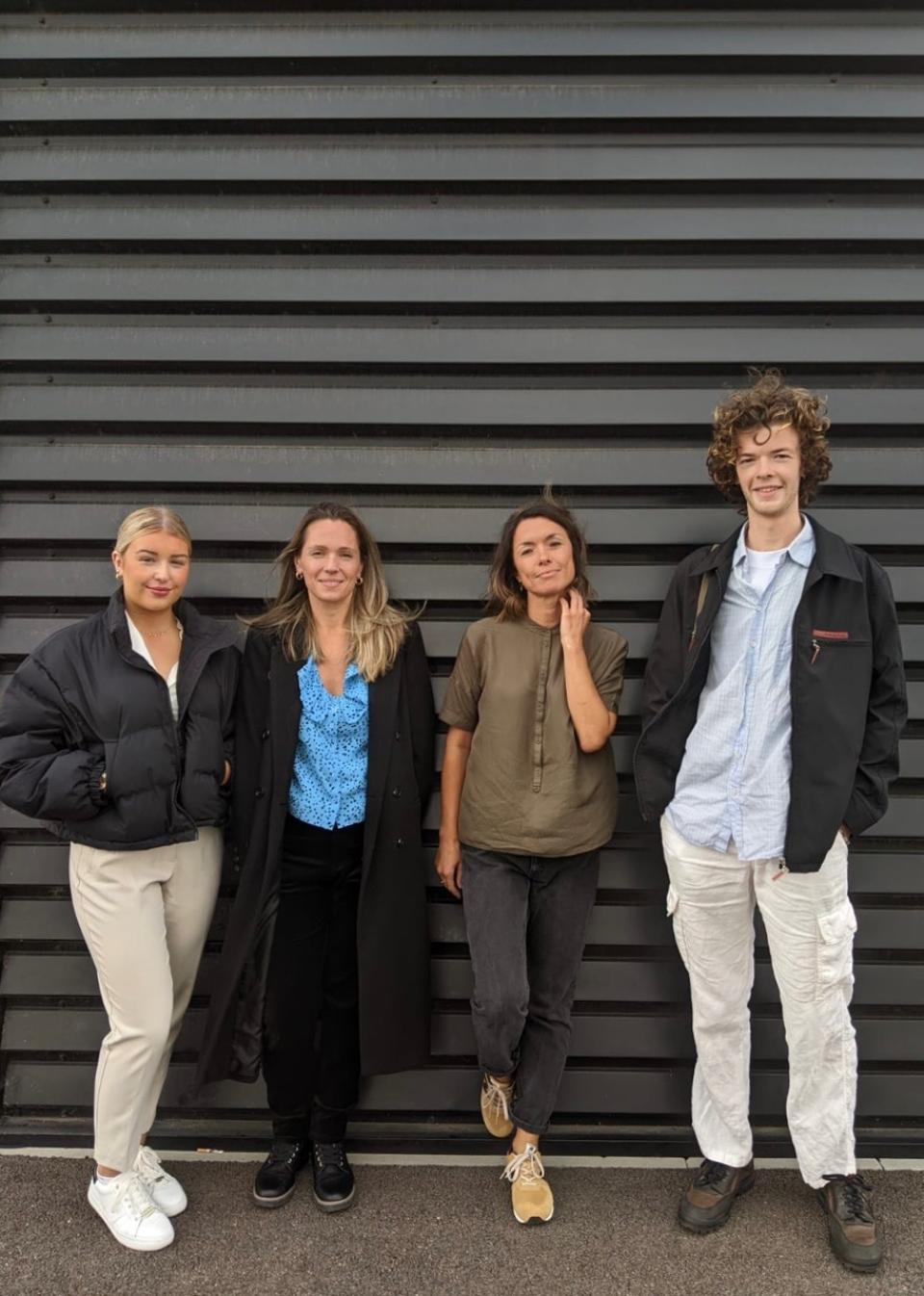 Four diverse team members from Auric Design stand confidently against a sleek black backdrop, embodying collaboration and creativity.