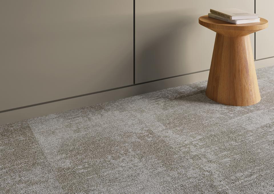 Stylish Tessera Infused carpet tiles paired with a modern wooden stool in a contemporary workspace setting.