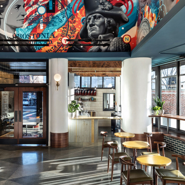 Vibrant interior design of The Revolution Hotel in Boston, featuring historic artwork and a modern café space.