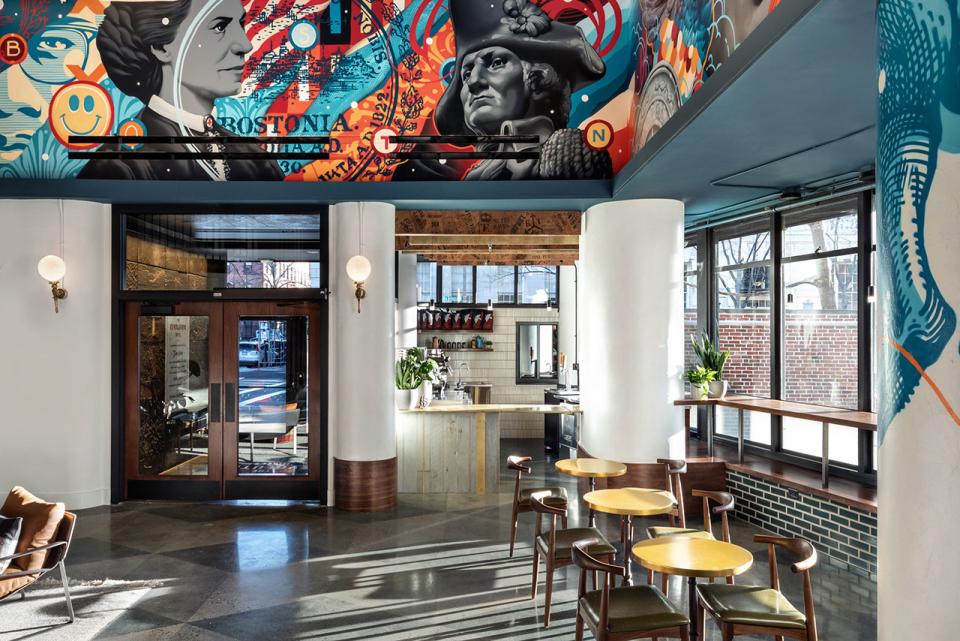 Vibrant interior design of The Revolution Hotel in Boston, featuring historic artwork and a modern café space.