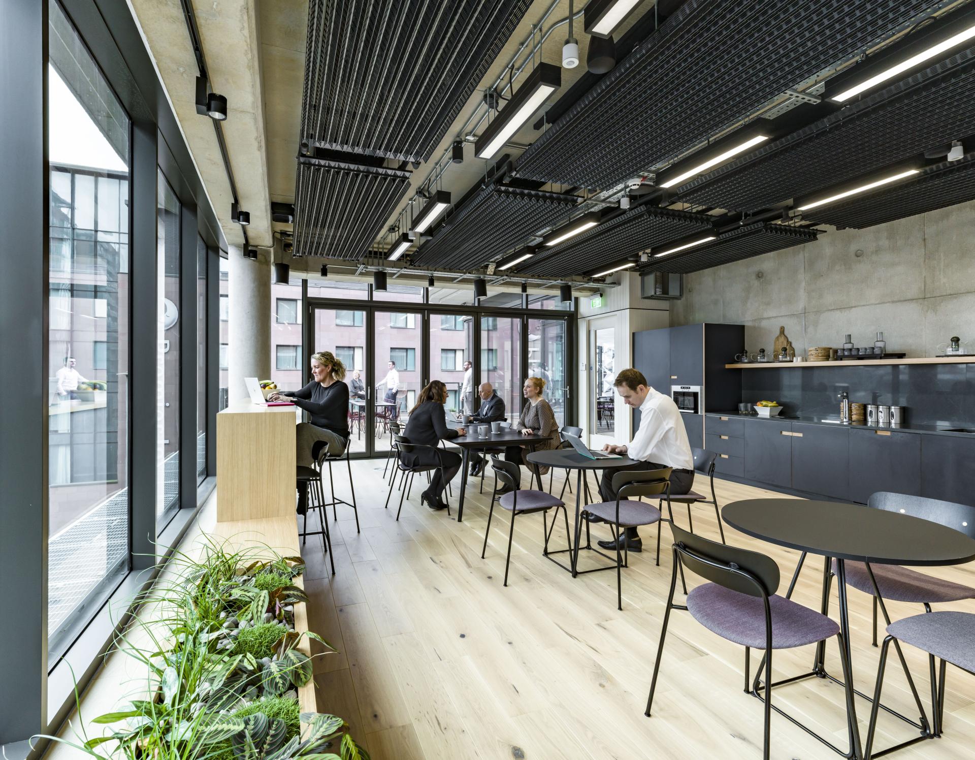 Stylish office interior at Riverside House with workers engaged at tables, showcasing modern design by SpaceInvader.