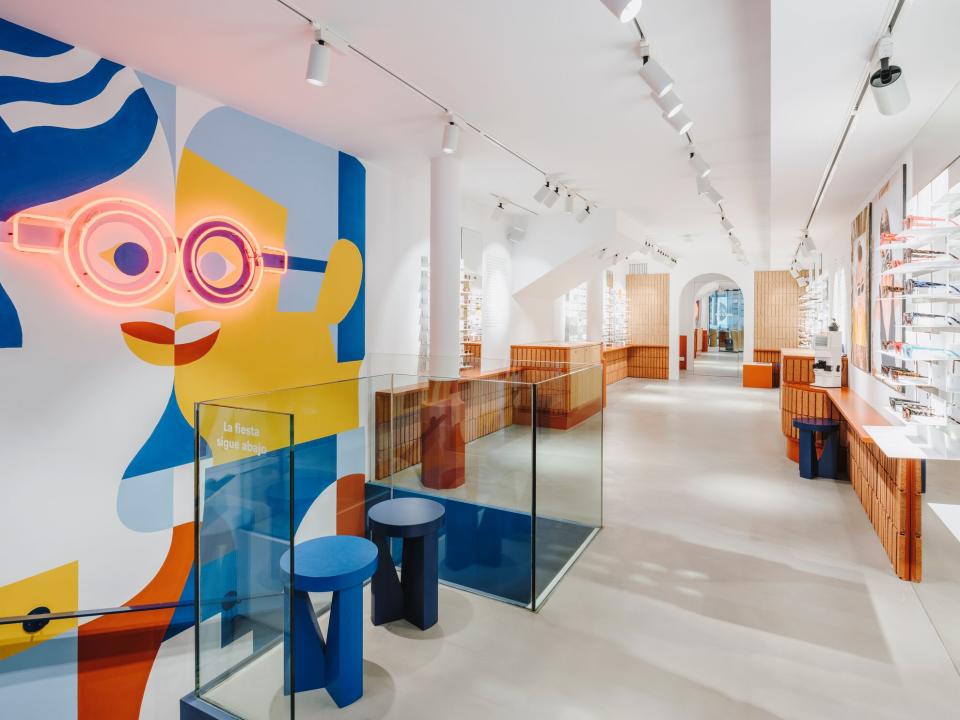 Brightly colored interior of ACE & TATE Barcelona, featuring decorative wall art and stylish eyewear displays.