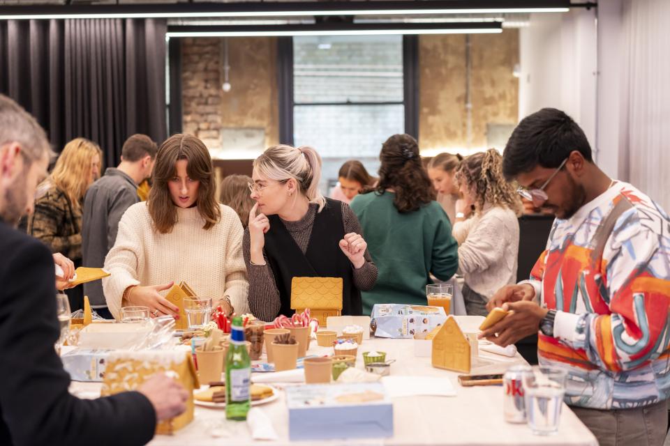 Participants engaged in a creative gingerbread house decorating workshop at Material Source Studio in Manchester.