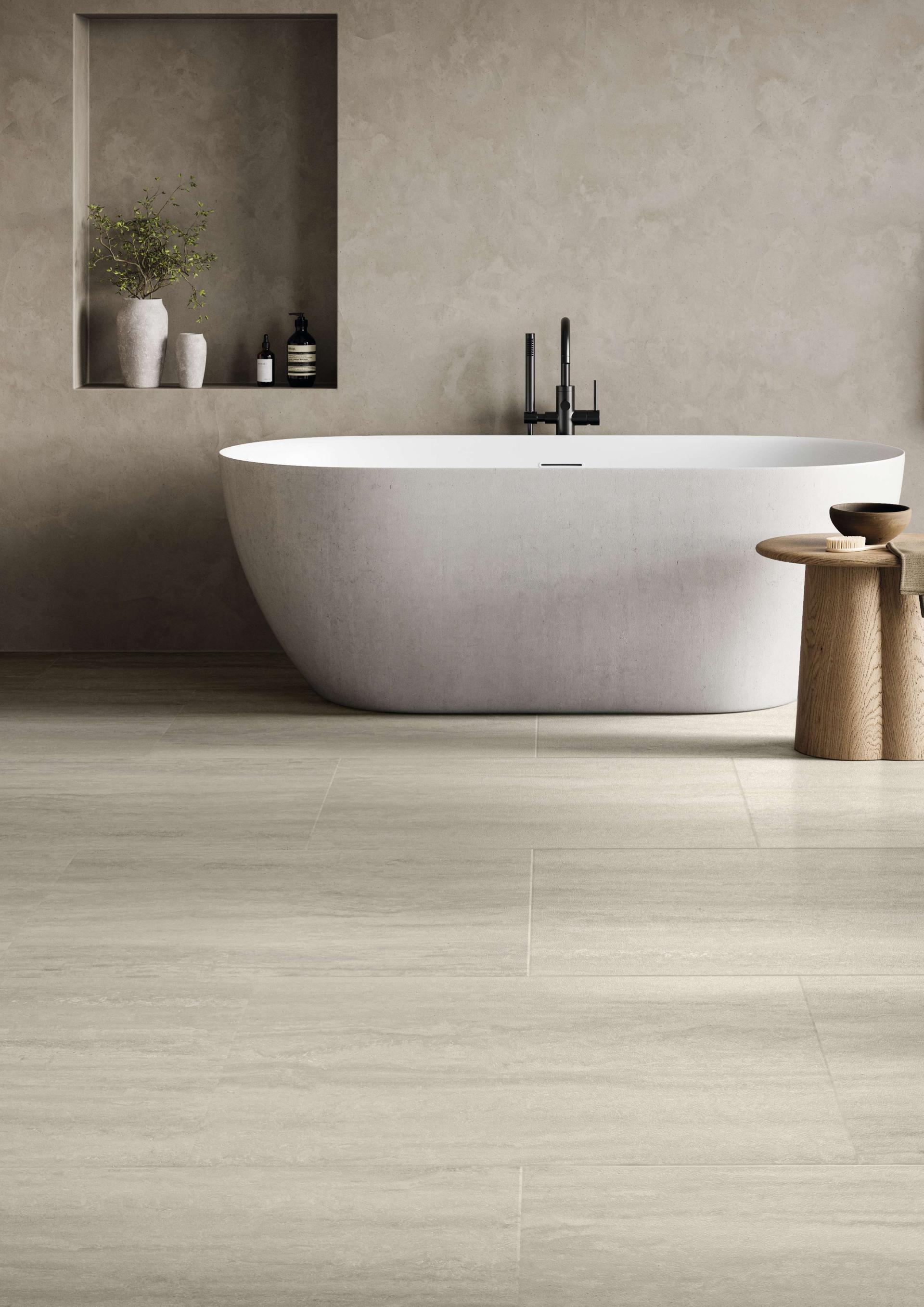 Elegant bathroom featuring a modern freestanding tub, wood accent table, and luxurious stone-style flooring.