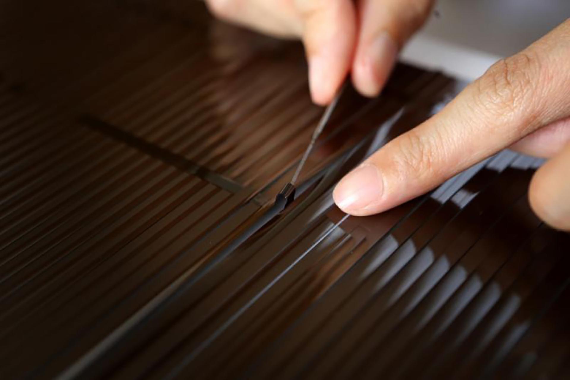 Hands carefully working on a dismantled cassette tape for up-cycling into new music projects.