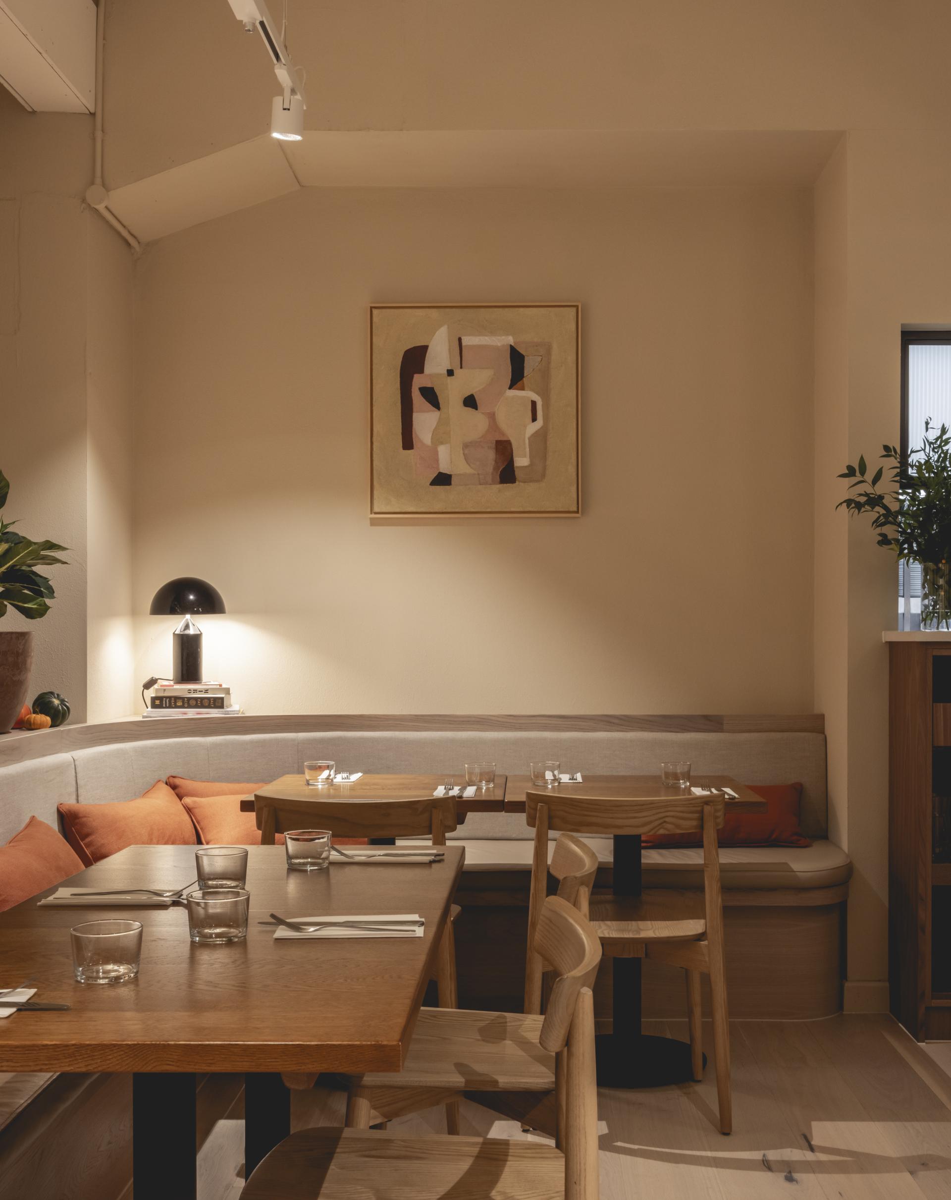 Stylish interior of Honey & Co's new deli featuring warm terracotta tones, wooden furniture, and contemporary artwork.