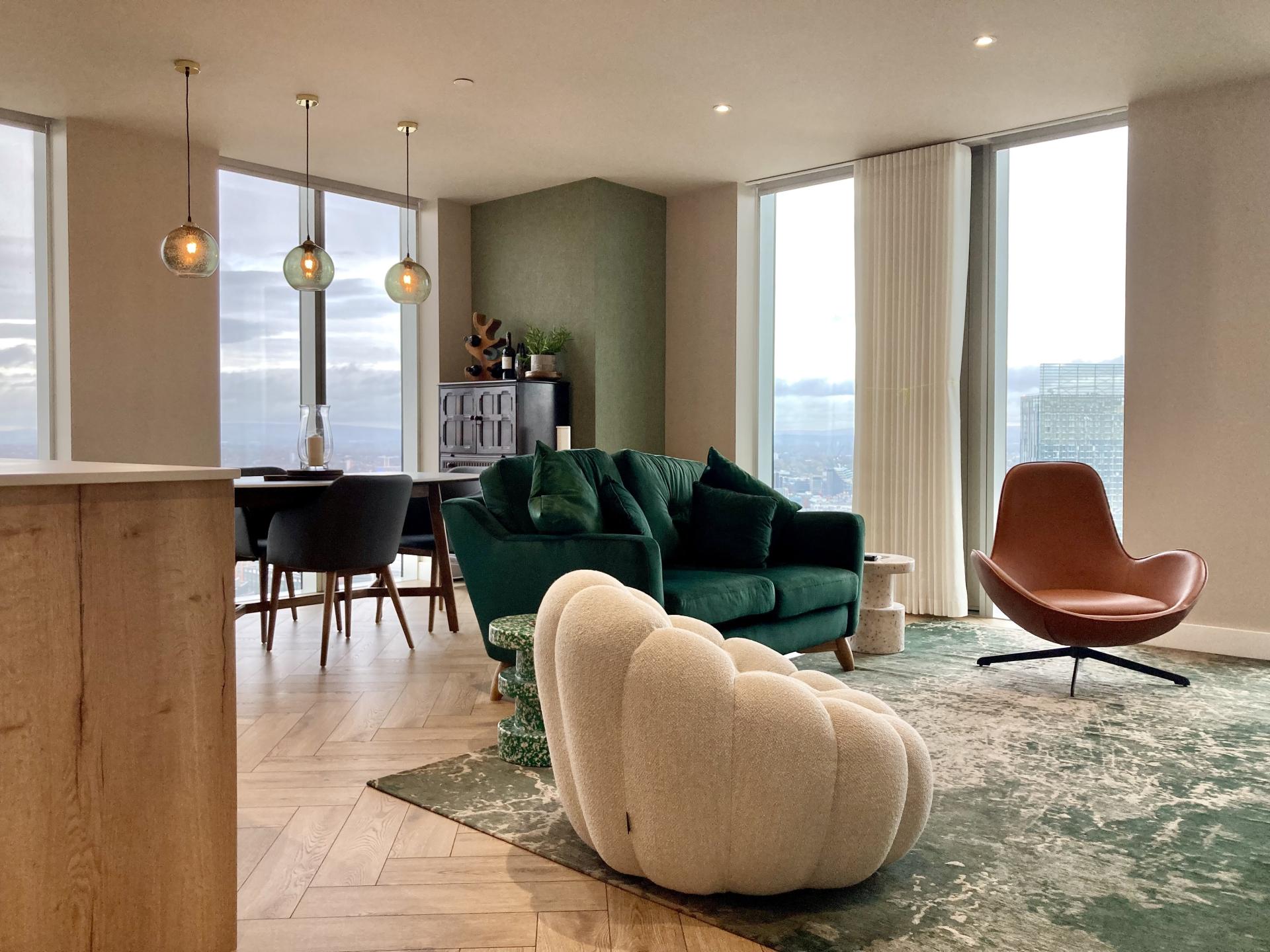 Stylish Manchester apartment interior featuring green and earthy tones, modern furniture, and large windows with urban views.