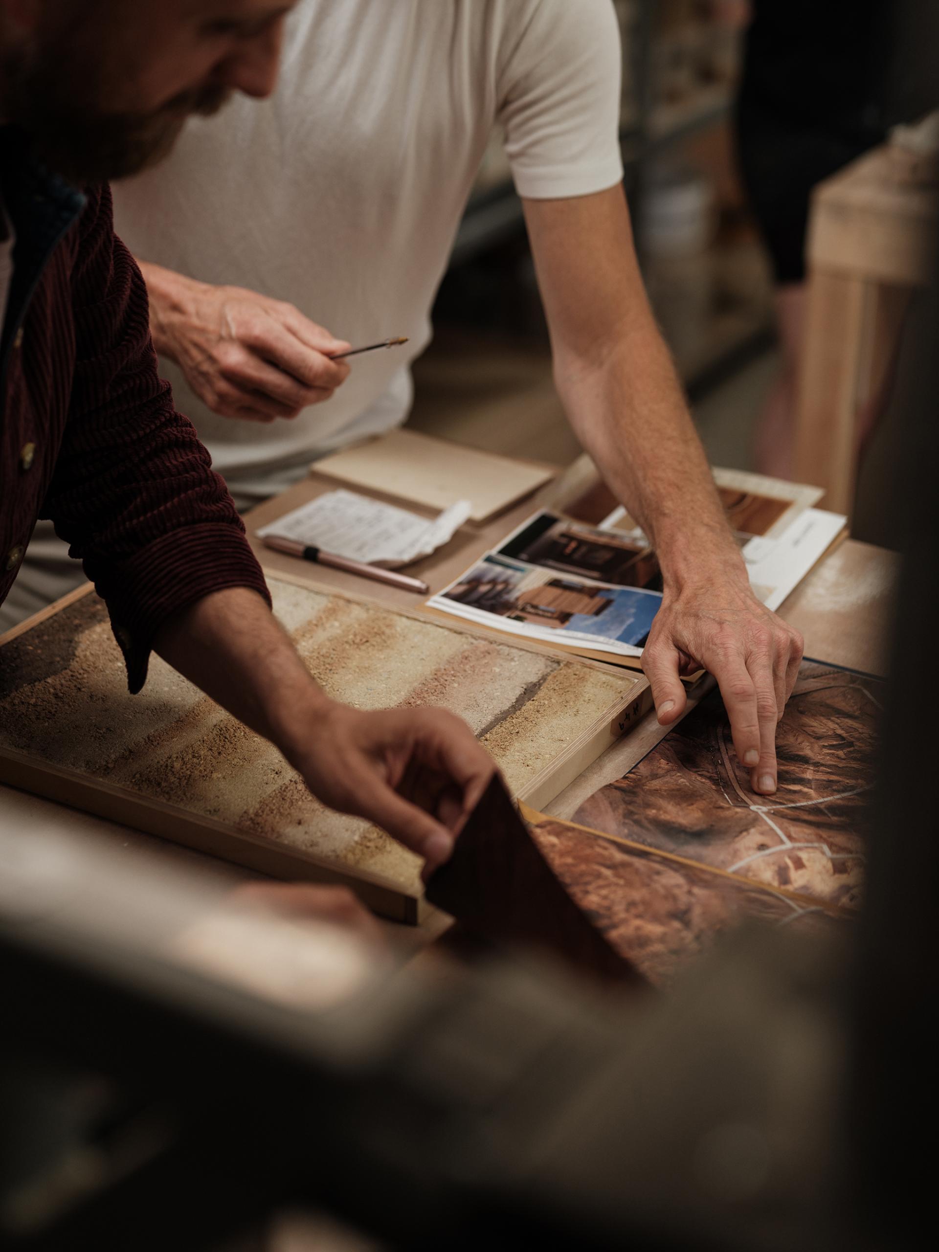 Designers discussing sustainable wall finishes while examining samples and color palettes inspired by rammed earth textures.