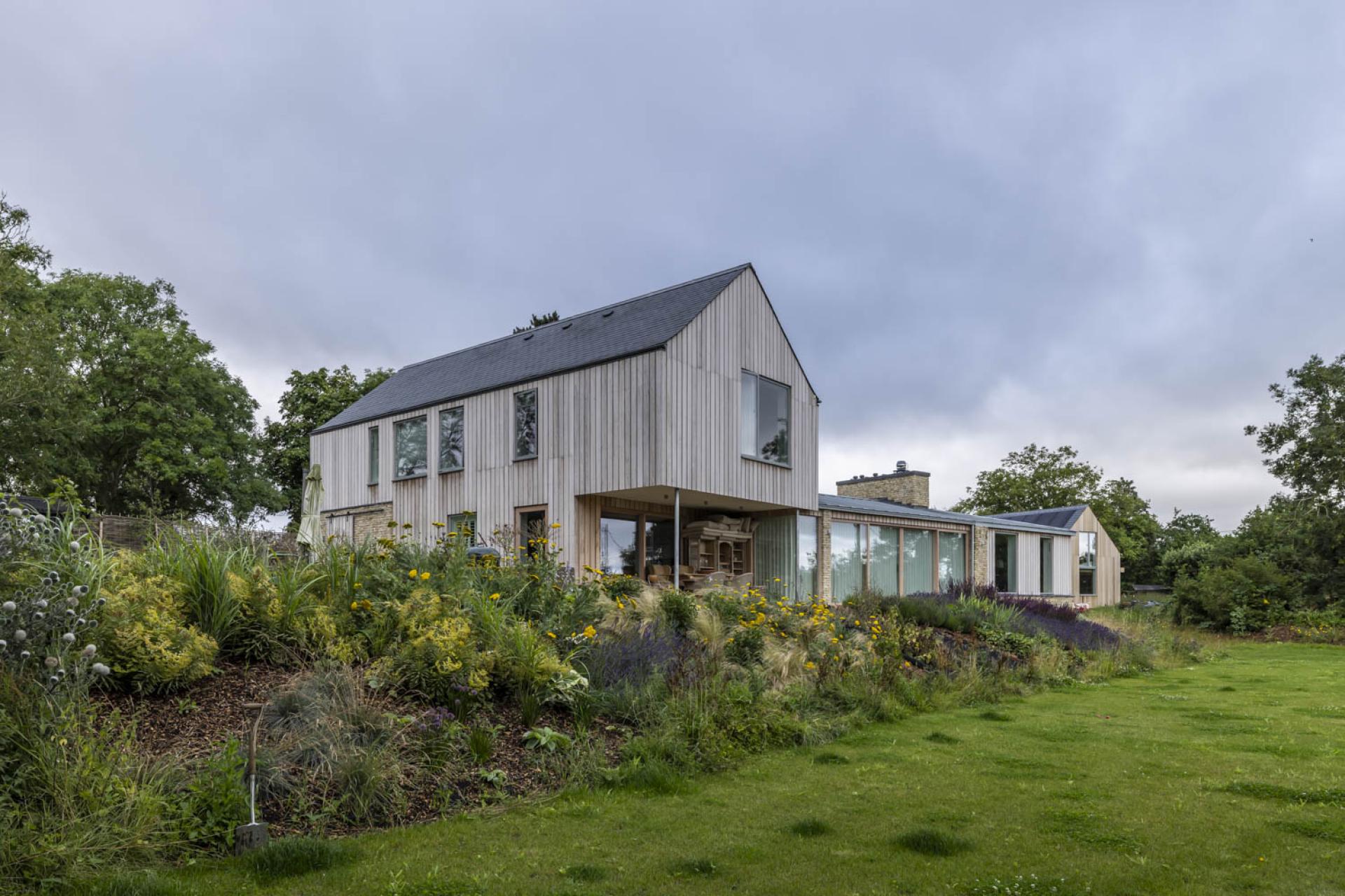 Modern wooden house blending with lush garden, showcasing European architectural beauty through natural surroundings and creative design.