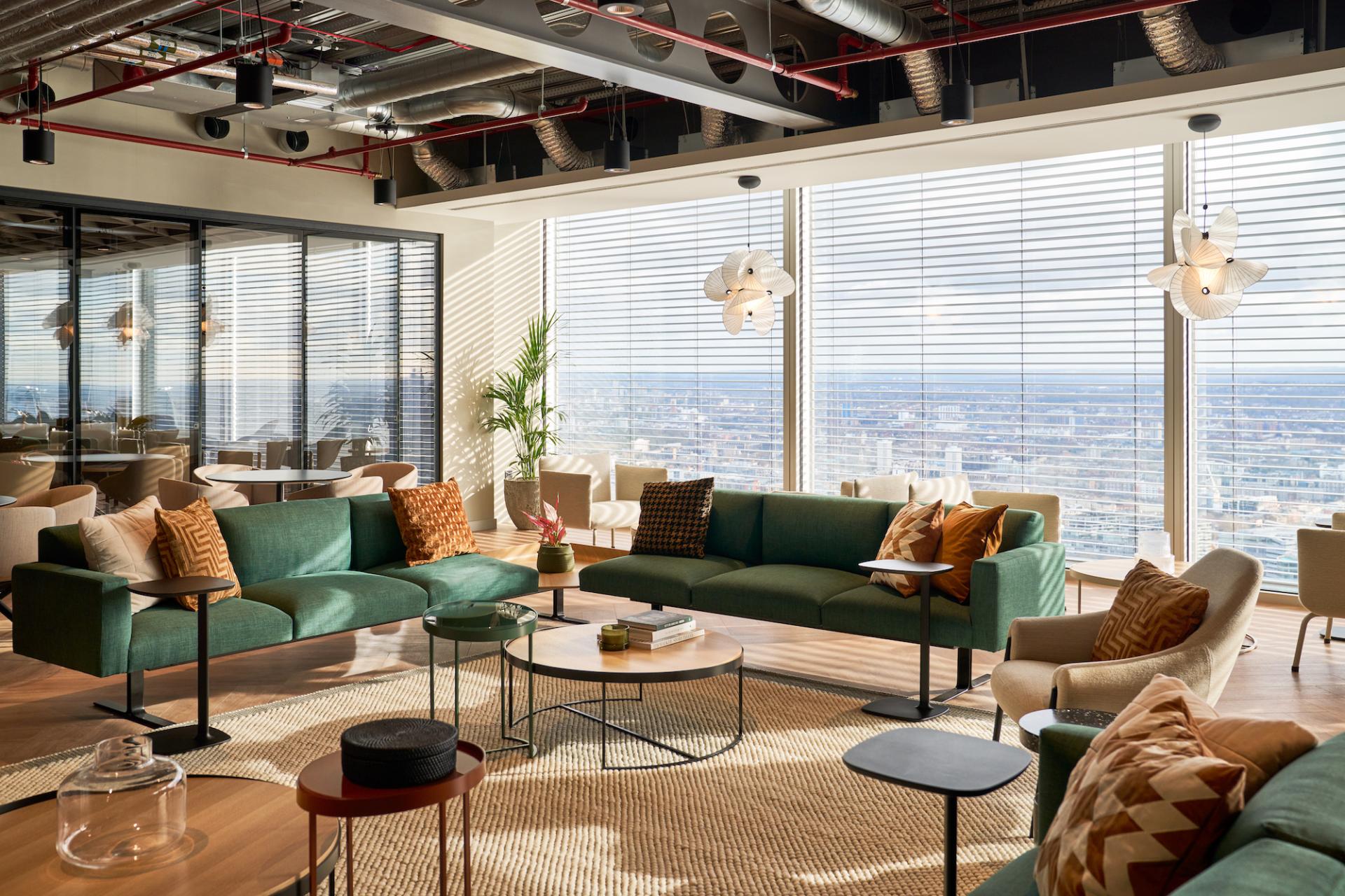 Modern workspace design featuring green seating, natural light, and city views, reflecting Bentley Systems' innovative office environment.
