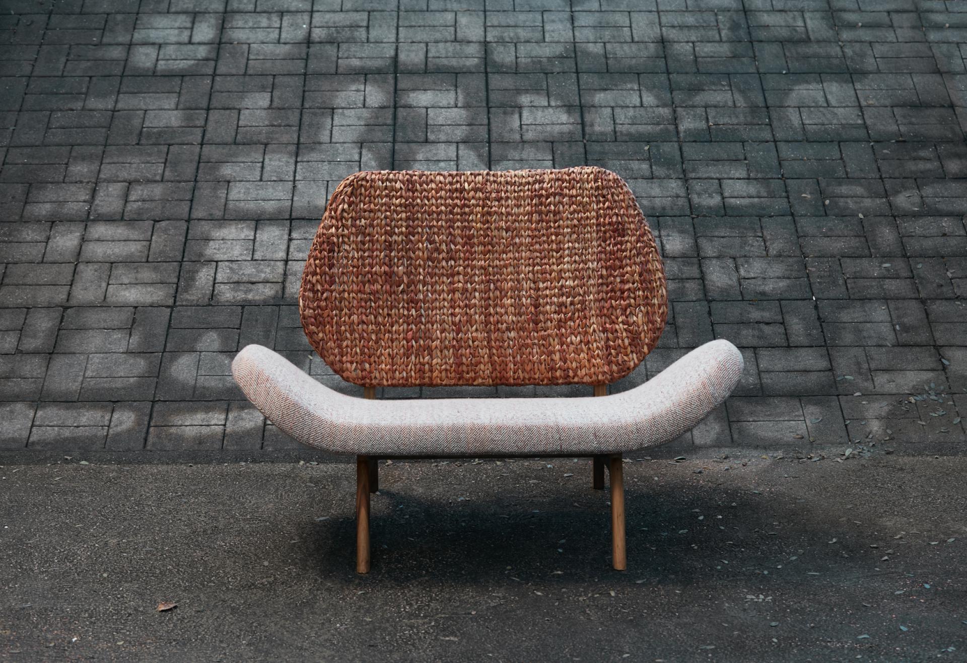 Tutura chair by Carolina Palombo featuring a wool seat and braided bullrush sedge back, set against a textured floor.