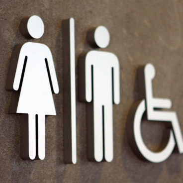 Signage depicting single-sex toilets and accessible facilities, highlighting building regulations for workplace inclusivity.