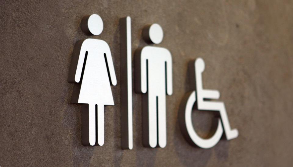 Signage depicting single-sex toilets and accessible facilities, highlighting building regulations for workplace inclusivity.