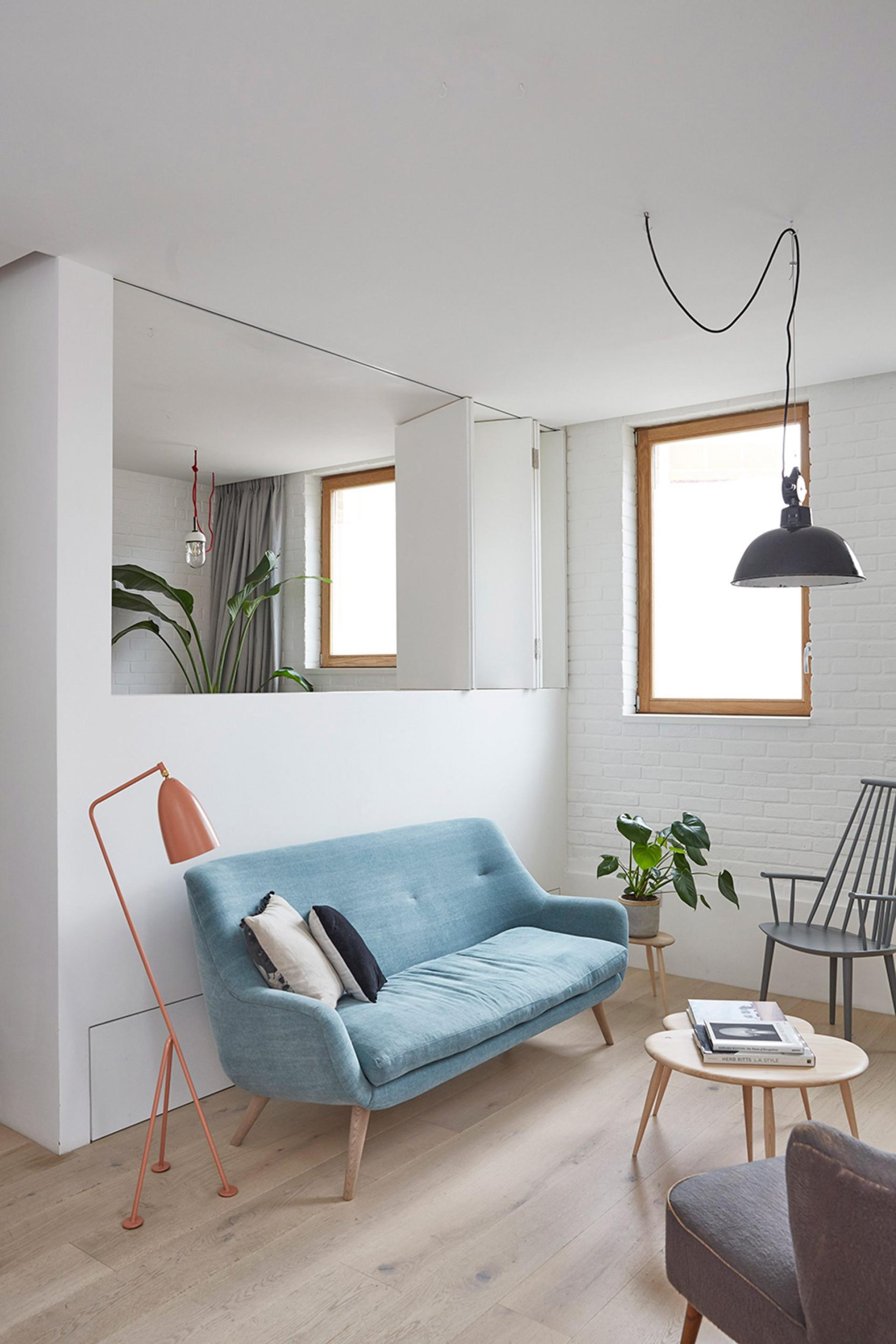 Revamped mews house interior featuring a calm design with a blue sofa, stylish furniture, and plants in Hackney.